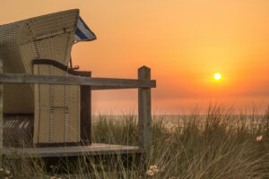 Serene beach view with wicker chair at sunset, capturing the beauty of nature and tranquility.